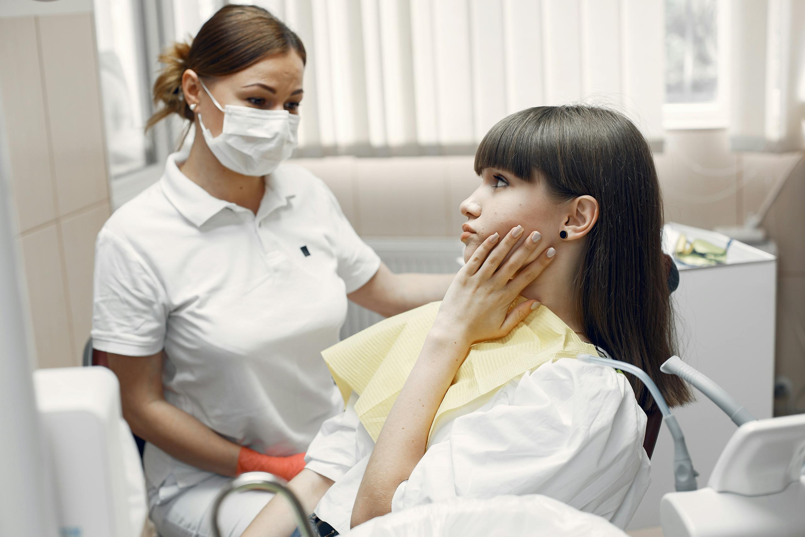 A dentist examining a young woman with toothache in a dental clinic.